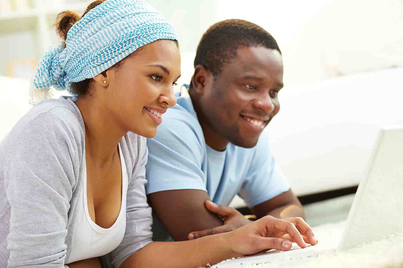 A man and a woman smiling as they look towards a laptop